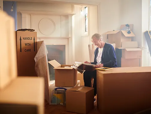 Homeowner with moving boxes in a newly downsized home, preparing for a fresh start.