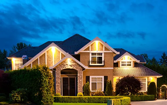 A beautiful home at night, lit up with soft lights that show off its elegant design and welcoming feel.