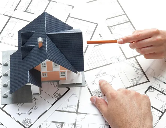 Custom property agents discussing plans using a house replica, illustrating development project details.