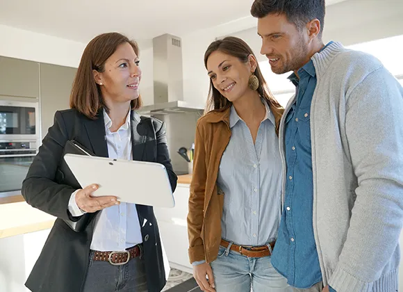 Property agent guiding a couple through real estate options on a tablet, providing expert advice.